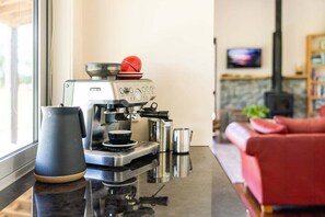 A modern kitchen with a coffee machine, a kettle, and a red couch in the background. - Greystoke Lodge - Dalefield (Dalefield)