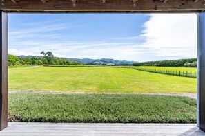 A covered outdoor area with a view of a green field and distant mountains.