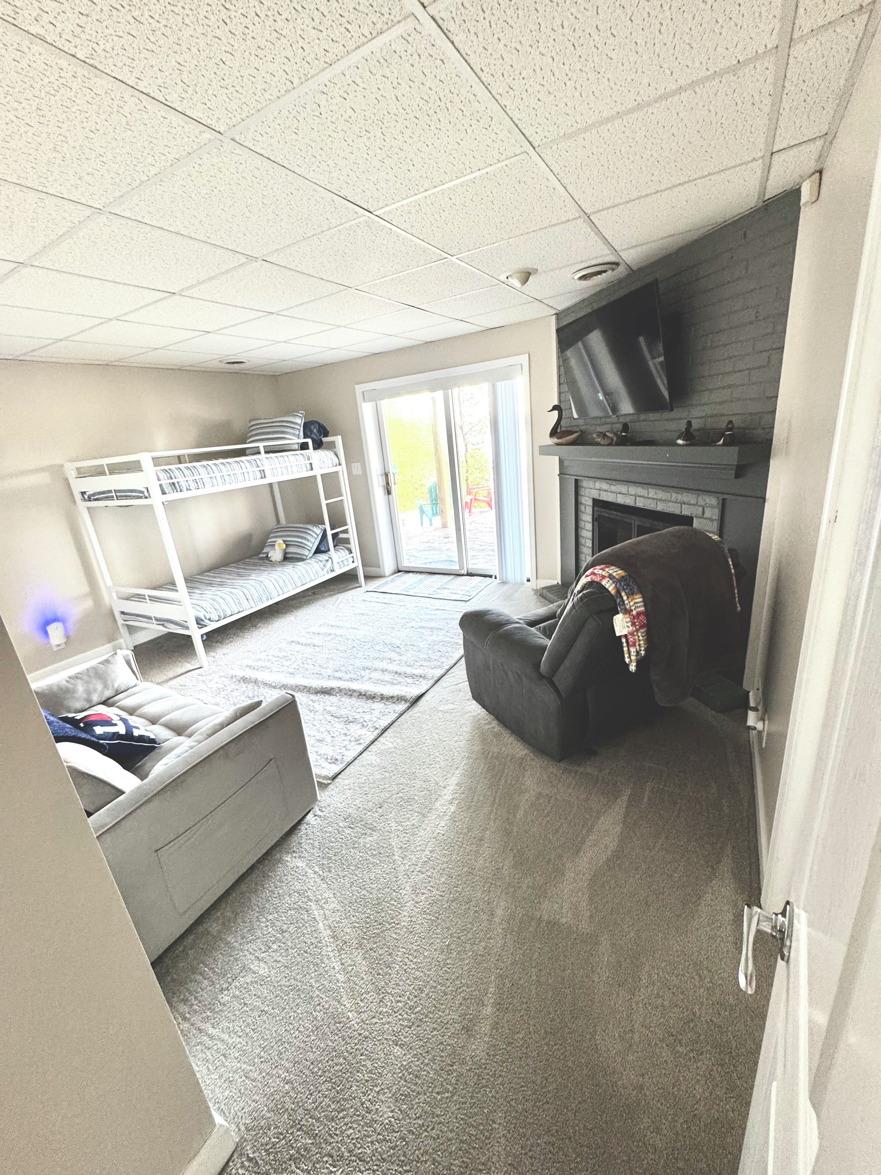 Ein Zimmer mit Etagenbetten, Kamin, Fernseher und einer Schiebetür zu einem Außenbereich.