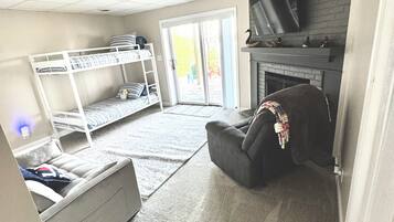 Ein Zimmer mit Etagenbetten, Kamin, Fernseher und einer Schiebetür zu einem Außenbereich.