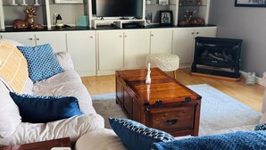Un salon avec un canapé, une table basse et un téléviseur posé sur un meuble.