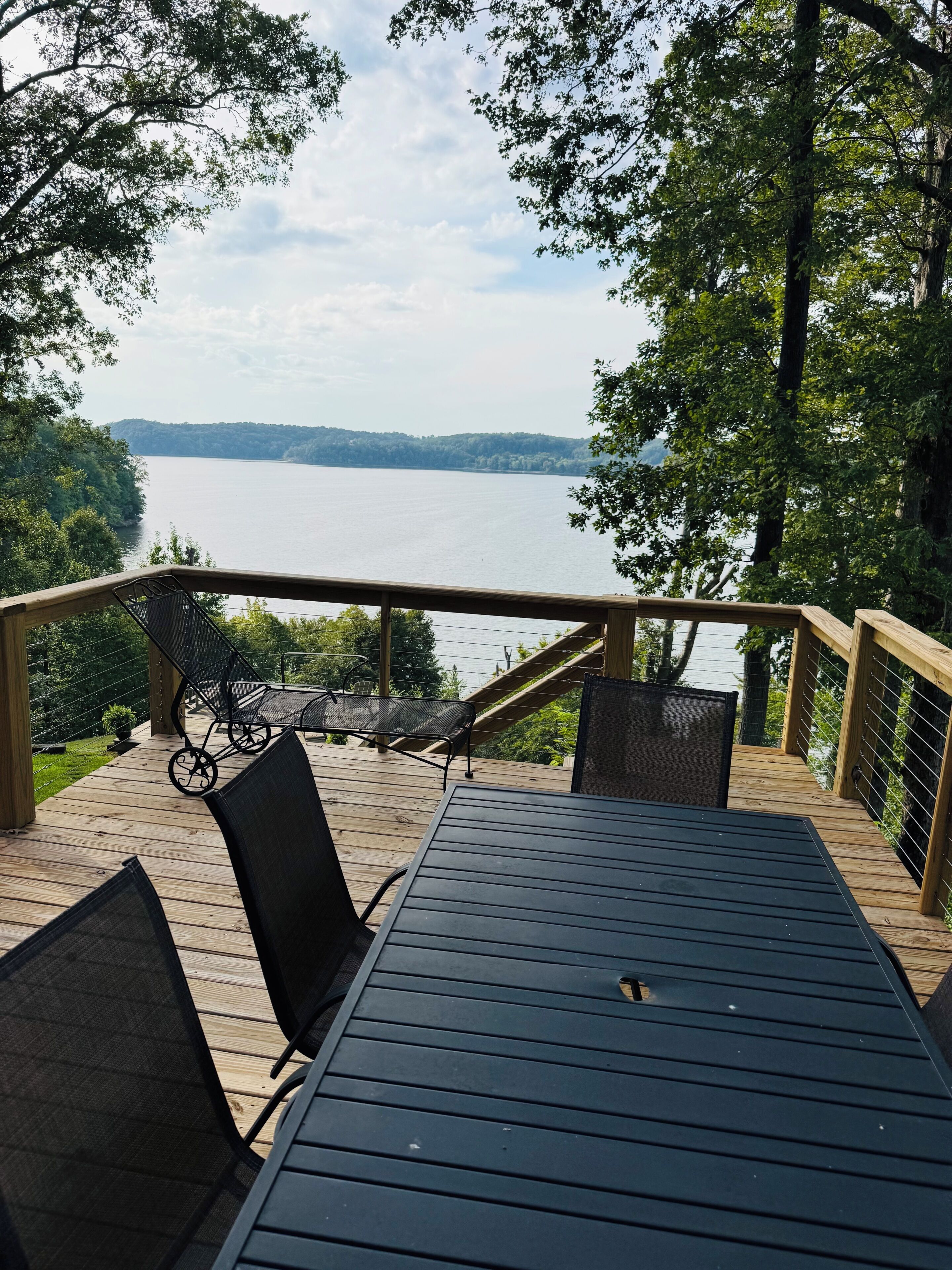 En træterrasse med bord og stole med udsigt over et søområde.
