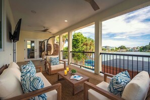 Un balcon spacieux offrant une vue sur un port de plaisance, aménagé avec un ensemble de canapés et une table à manger.