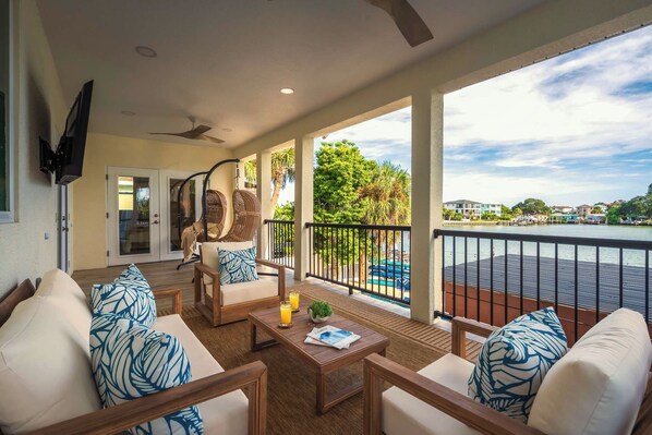 A spacious balcony with a view of a marina, furnished with a sofa set and a dining table. - Indian Rocks Beach New Waterfront Heated Pool & Spa  Golf Cart E-Bikes Kayaks Game Room Fire Pit Walking Distance to the Beach (Indian Rocks Beach)