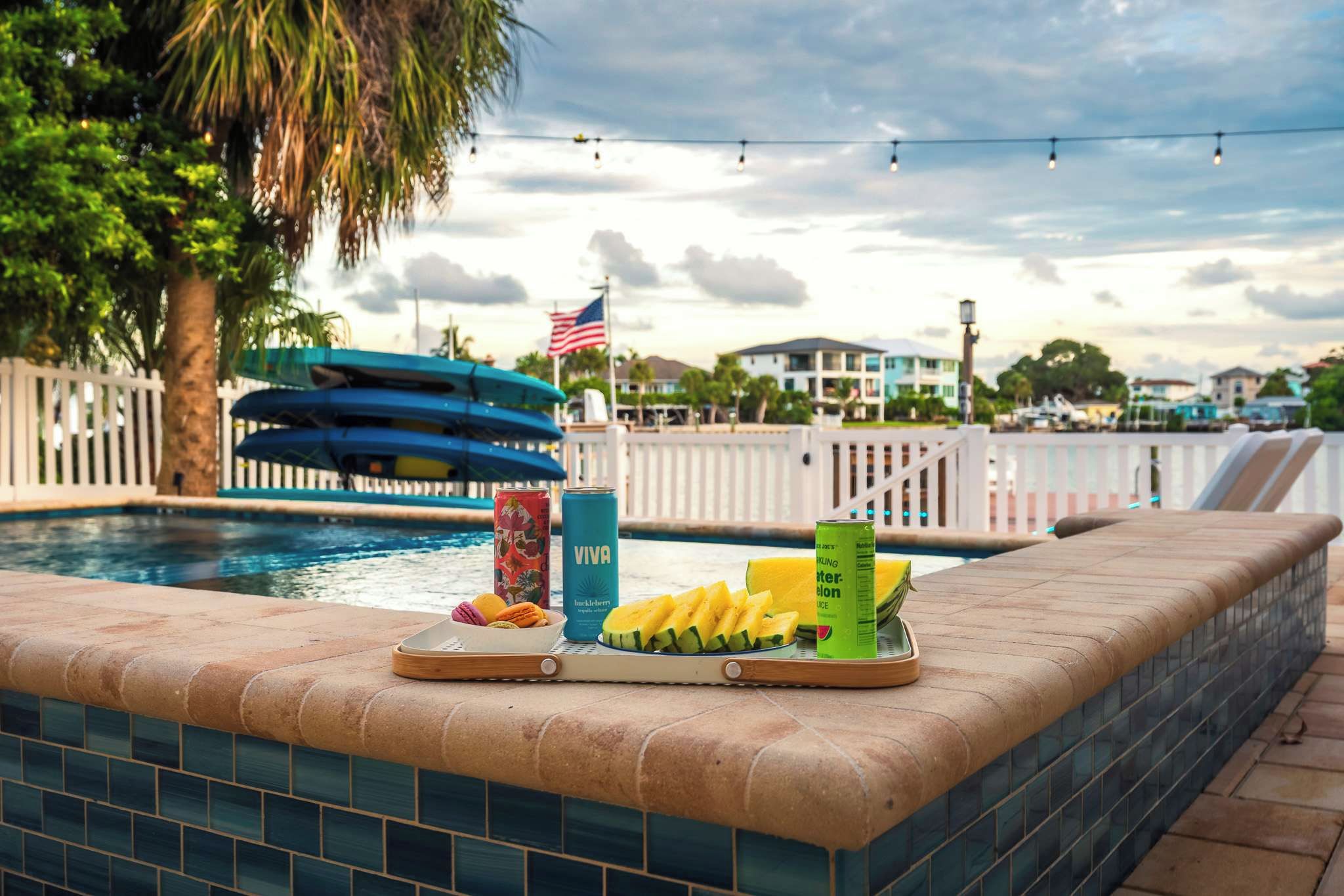 A poolside area with a water slide, a flag, and a tray with snacks and drinks.