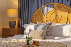 A neatly made bed with a rattan headboard, a bedside lamp, and a cup of coffee on a fluffy blanket. - Indian Rocks Beach New Waterfront Heated Pool & Spa  Golf Cart E-Bikes Kayaks Game Room Fire Pit Walking Distance to the Beach (Indian Rocks Beach)
