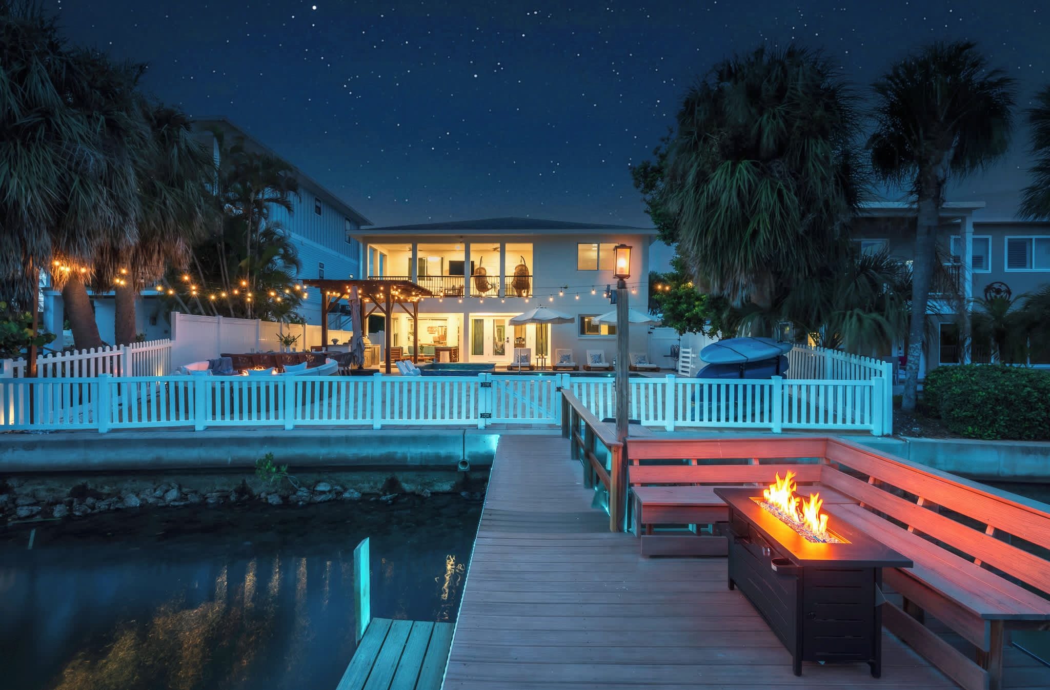 A waterfront property with a dock, outdoor seating, and a pool.