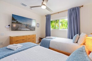 A hotel room with two beds, a ceiling fan, a beach-themed painting, and a window with curtains. - Indian Rocks Beach New Waterfront Heated Pool & Spa  Golf Cart E-Bikes Kayaks Game Room Fire Pit Walking Distance to the Beach (Indian Rocks Beach)