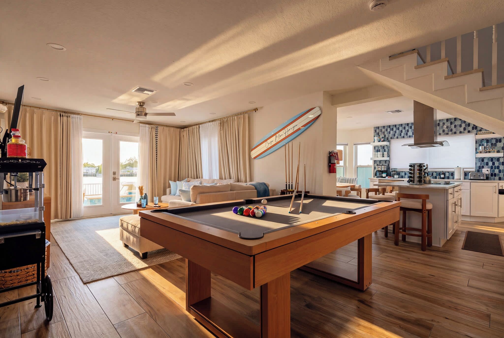 Un salon moderne comprenant une table de billard, un coin repas et une cuisine.