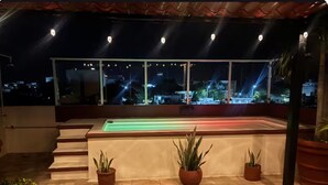 Eine Dachterrasse mit Pool, Sitzgelegenheiten und Pflanzkübeln.
