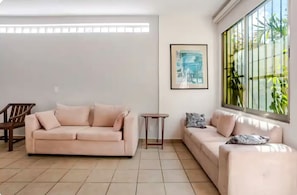 A living room with two sofas, a wooden chair, a small table, and a framed picture on the wall. - El Coral: apartment with rooftop lounge access minutes from 5 Avenida (Playa del Carmen)