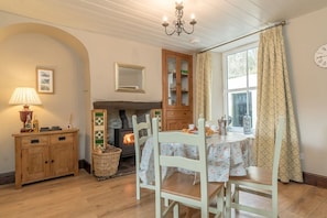 A cozy room with a fireplace, wooden furniture, and a dining table set for two. - Views over Yr Wyddfa (Snowdon)  and the Welsh Highland Railway | Bron-Eifion (Rhyd Ddu)
