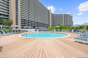 A pool area with a wooden deck, lounge chairs, and umbrellas. - Direct Garage Access, Lake View & 5 Pools | Laketown Wharf 226 (Panama City Beach)