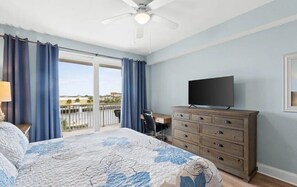 Une chambre à coucher avec un lit, une commode, un téléviseur et un bureau.