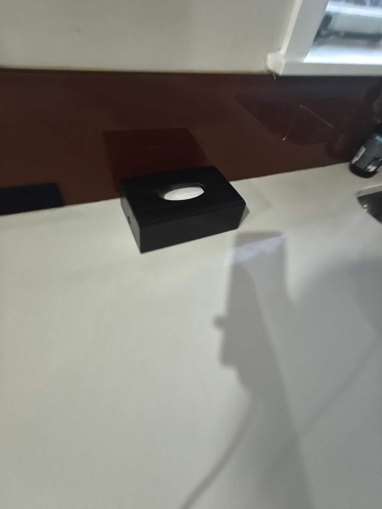 A black object on a white surface, possibly a box or container.