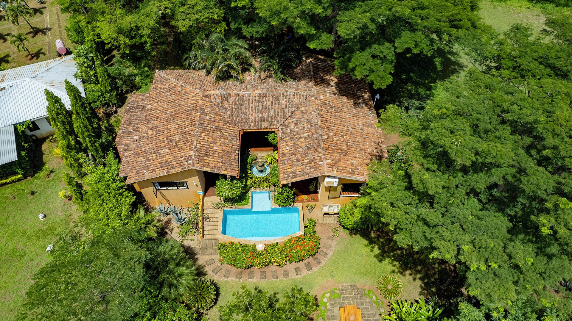 A house with a swimming pool, surrounded by lush greenery.