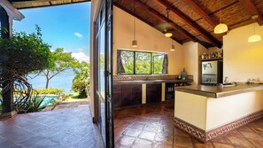 Une cuisine avec vue sur la mer, un grand îlot central et un luminaire suspendu.