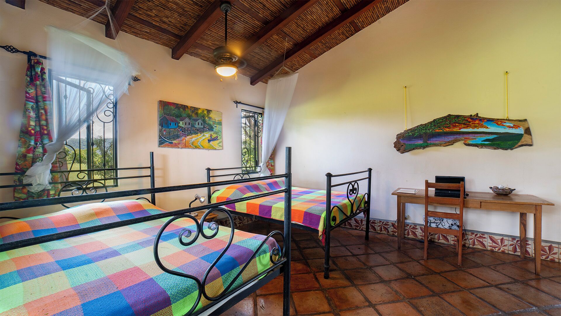 A room with two metal beds, a wooden desk, and a chair.