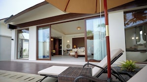 A modern outdoor seating area with wicker furniture and a glass door leading to an interior space.