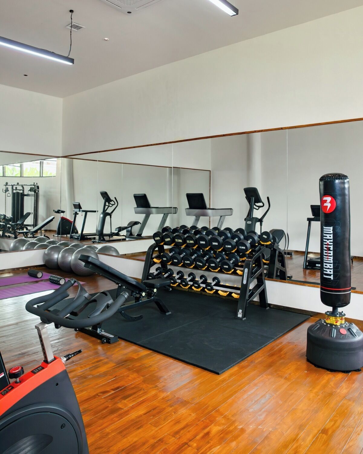 Een sportschool met trainingsapparatuur, een bokszak en een spiegel.