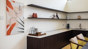 A modern kitchen with dark wood cabinets, a white countertop, and a hanging artwork.