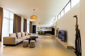 A modern living room with a sofa, ottomans, a coffee table, and a television. - Amayi Resort Nusa Dua (Bali)