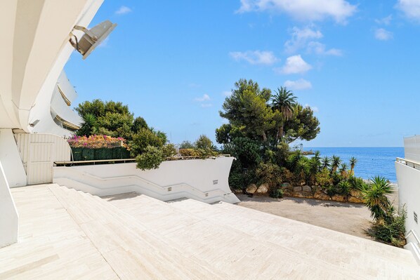 Un edificio blanco con una escalera que conduce a un balcón con vistas al agua.