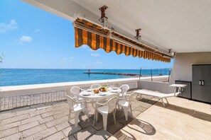 Een terras met een eettafel, met uitzicht op de kust.