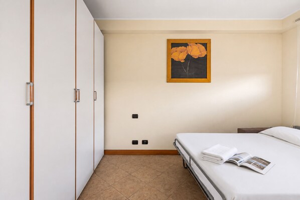 Een hotelkamer met een bed, een kast, een schilderij aan de muur en een betegelde vloer.