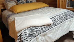 Une chambre dans une cabane en bois, avec un lit, des oreillers et une étagère remplie de livres.