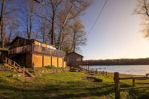 A wooden cabin with a balcony, a smaller adjacent building, and a dock extending into a lake. - Lake House on Bluff Lake - Nature Lovers Paradise (Lake)