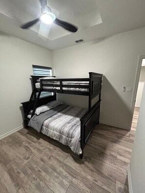 A bunk bed with a ladder, a ceiling fan, and a window with blinds. - Comfortable & Cozy Home Donna, TX (Donna)