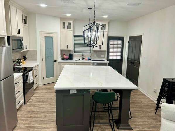 Een moderne keuken met witte kastjes, een centraal eiland en een hangende lamp.