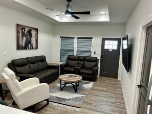 A living room with a sectional sofa, a white armchair, a coffee table, and a ceiling fan. - Comfortable & Cozy Home Donna, TX (Donna)