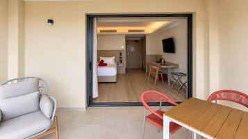 A hotel room with a bed, a desk, a chair, and a television.