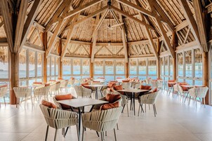 Un espacio interior amplio con techos altos, ventanas grandes y vista al mar.