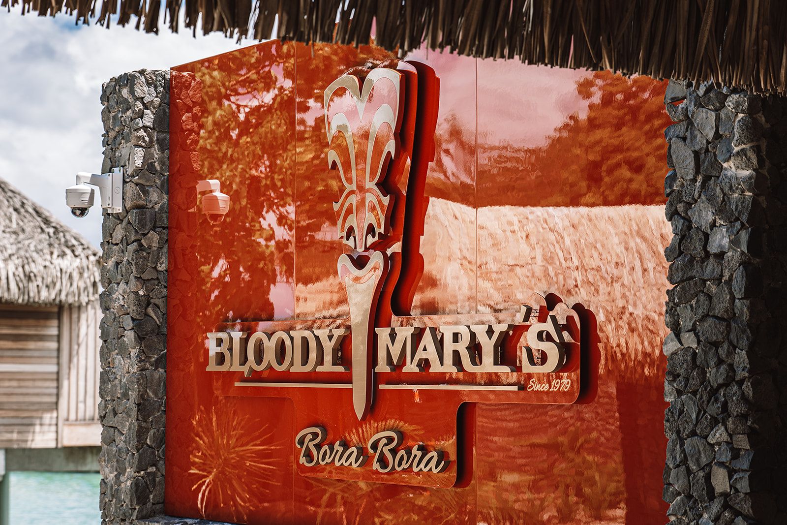 A sign for Bloody Mary's with a stylized knife graphic, located at the entrance of a building with stone walls.