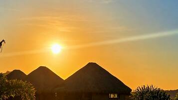 Ein Resort mit Bungalows über dem Wasser, einem Swimmingpool und Blick auf den Sonnenuntergang.