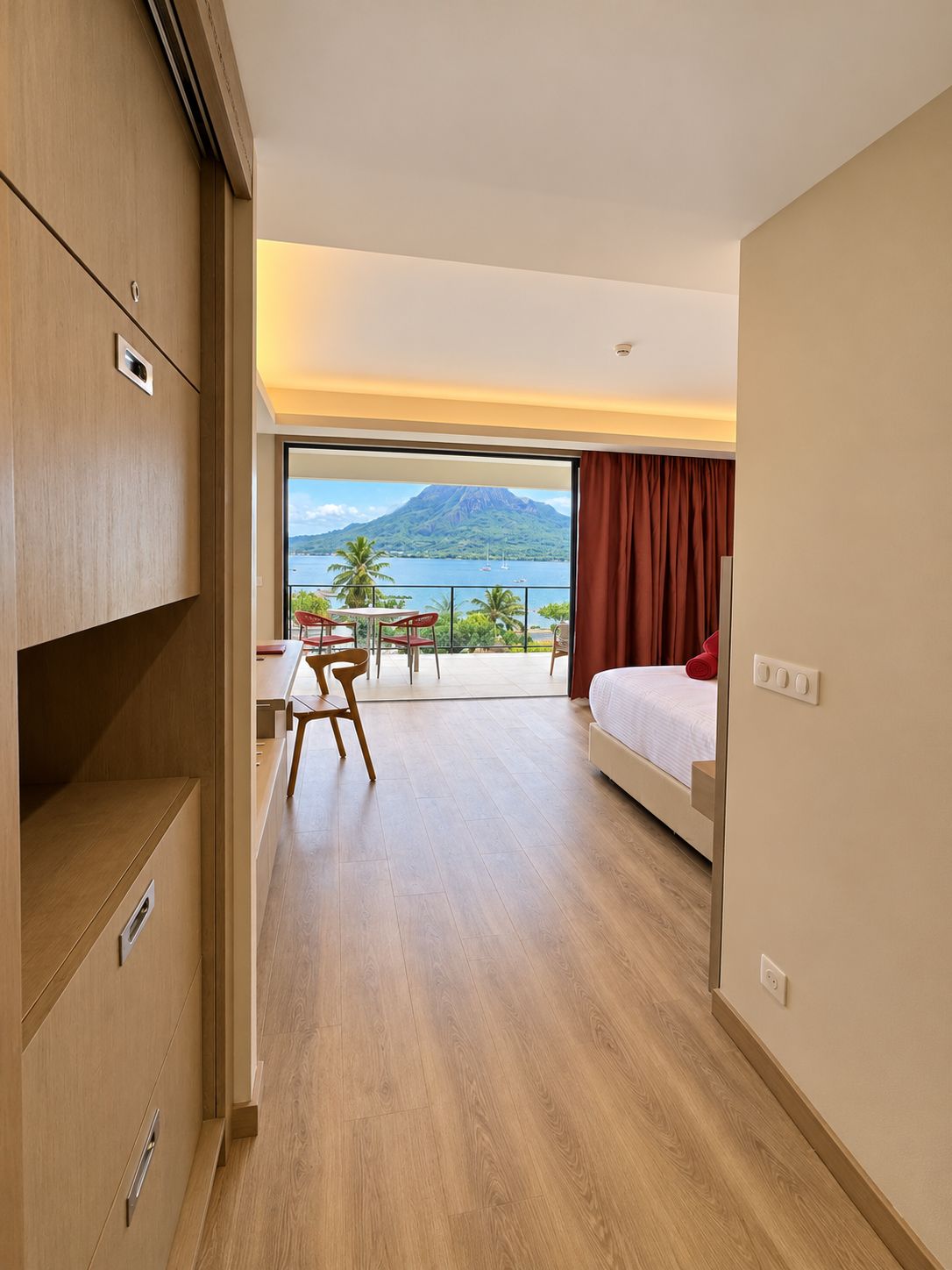 Una habitación de hotel con cama, escritorio y vistas a una montaña y al agua.