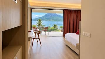 Una habitación de hotel con cama, escritorio y vistas a una montaña y al agua.