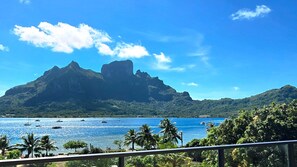 A coastal view with a mountain, clear sky, and boats on the water. - Bloody Mary's Hotel (Bora Bora)