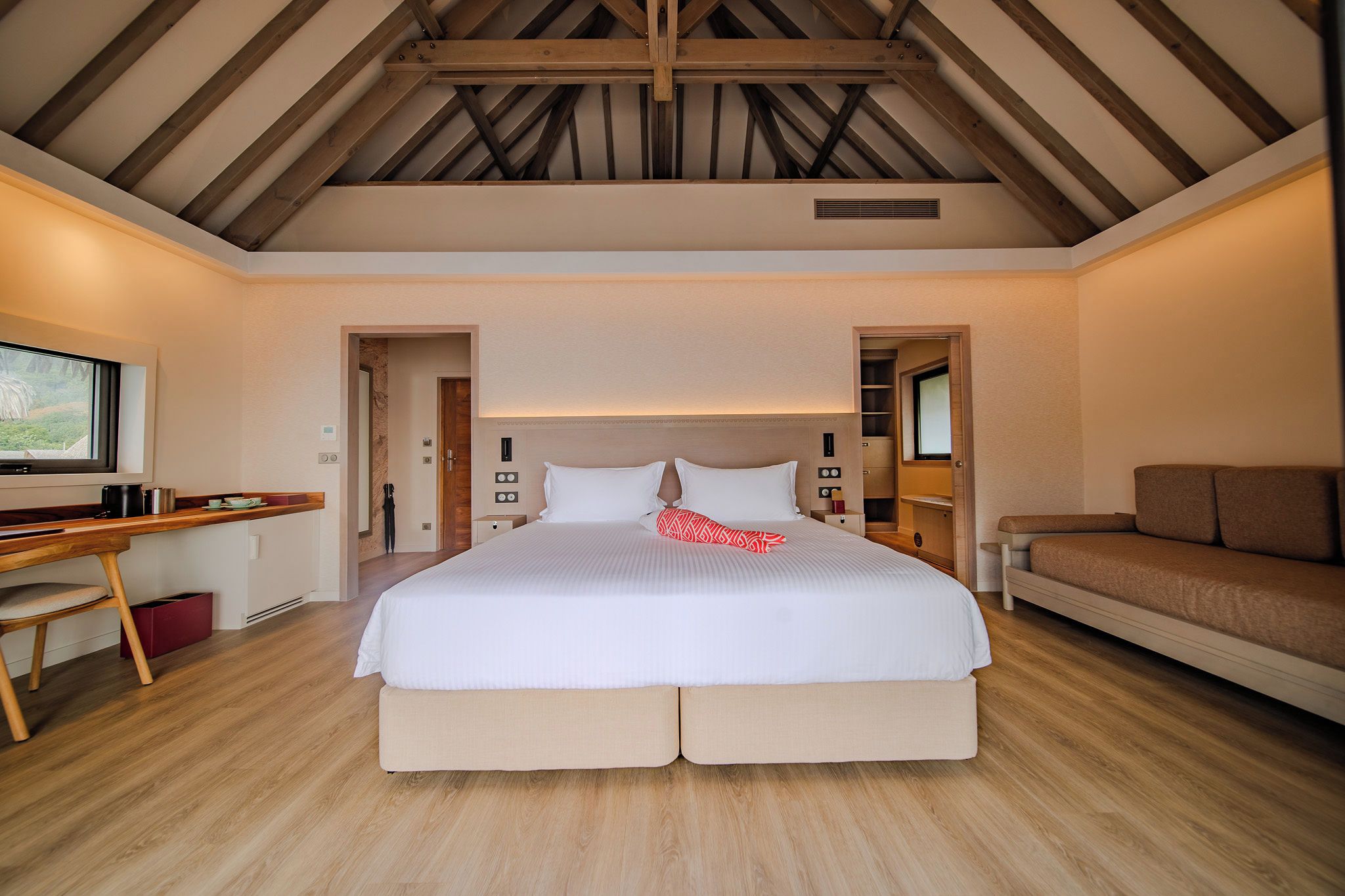 Un dormitorio con una cama grande, un escritorio, un sofá y vistas al exterior.
