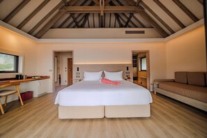 A bedroom with a large bed, a desk, a sofa, and a view of the outdoors. - Bloody Mary's Hotel (Bora Bora)