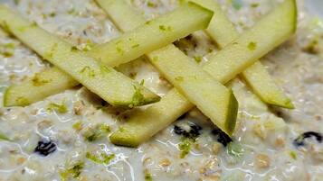 A bowl of oatmeal with apple slices and raisins.