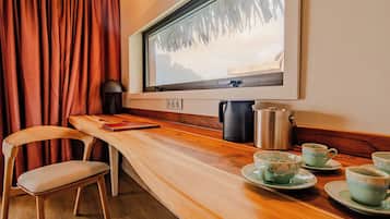 A cozy kitchen with a wooden countertop, a window with a view of trees, and a kettle.