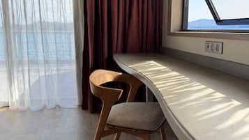 A room with a window, a table, and a chair.