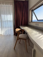 Una habitación con ventana, una mesa y una silla.