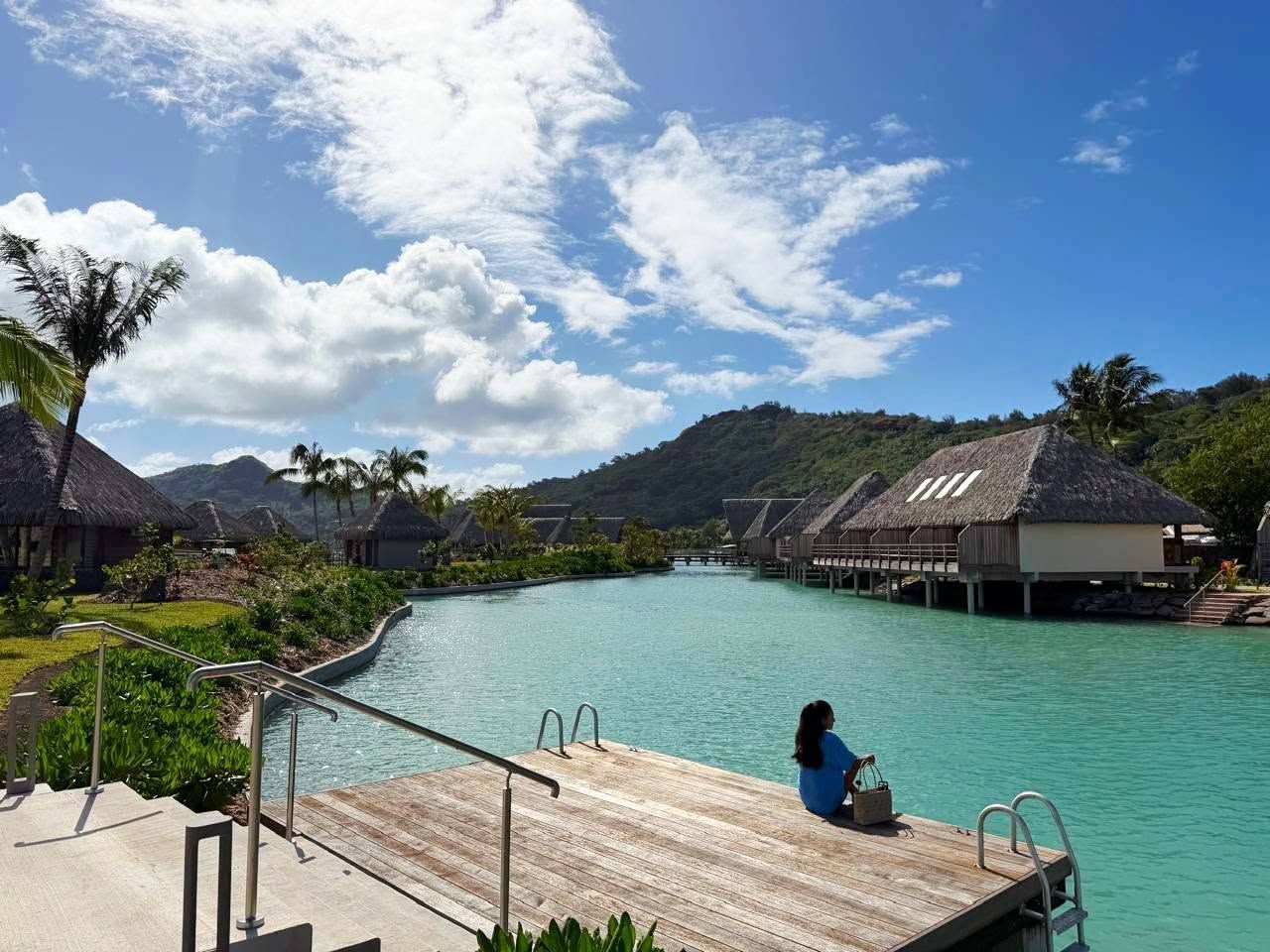 Un resort con bungalows sobre el agua, una piscina y una terraza de madera.