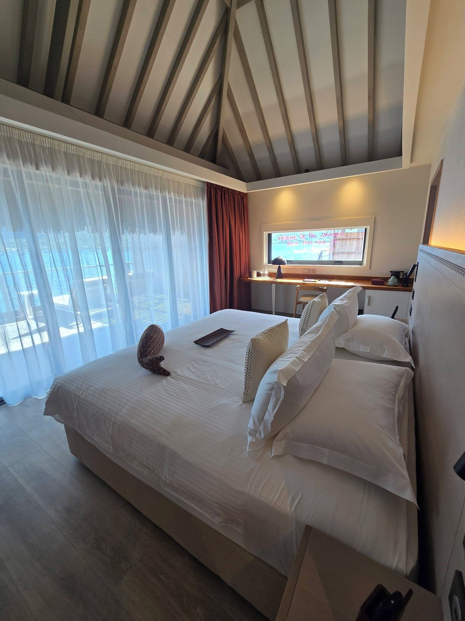 A hotel room with a large bed, a desk with a computer, and a view of the outdoors.