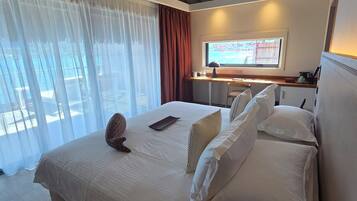 A hotel room with a large bed, a desk with a computer, and a view of the outdoors.